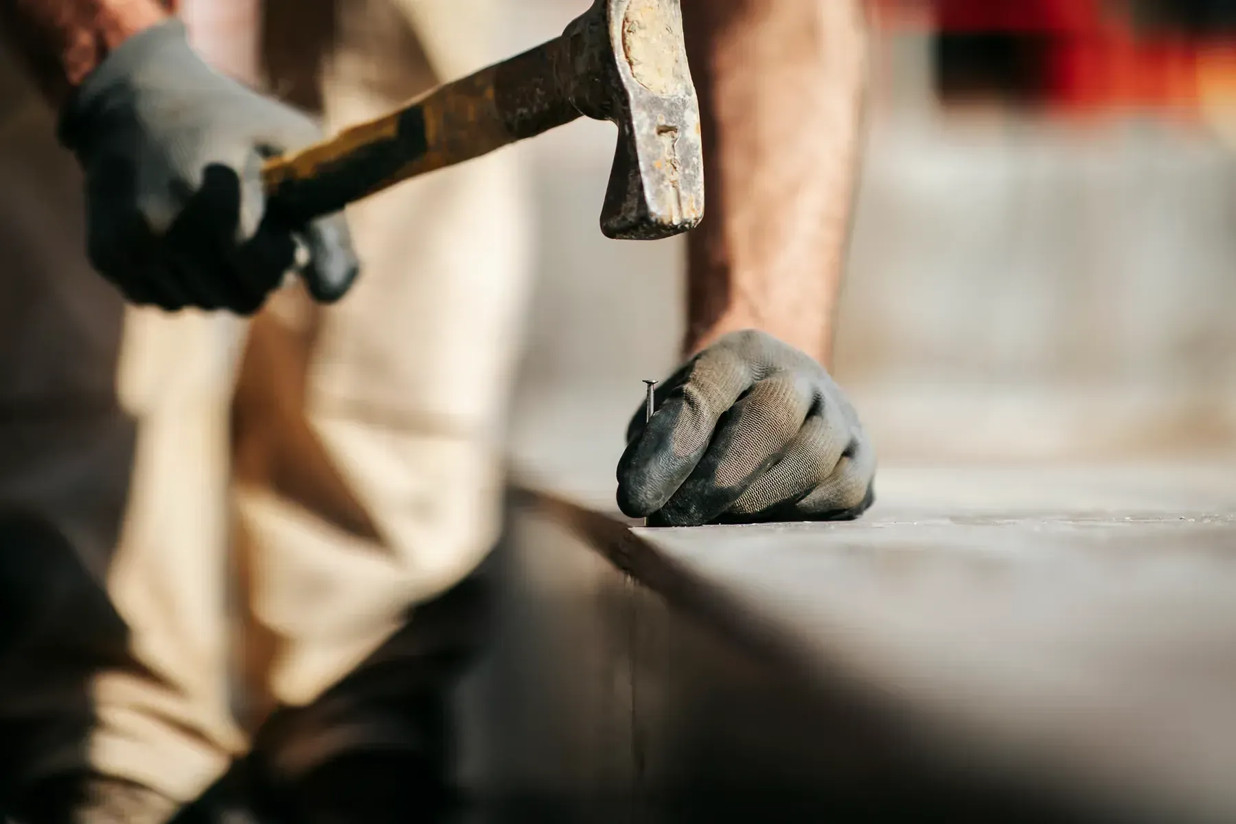 Gros plan sur une main gantée tenant un marteau de maçon