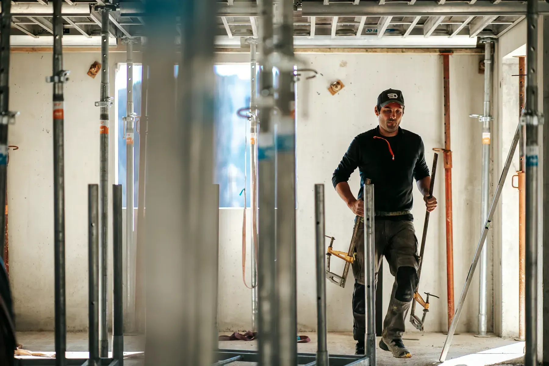 Maçon de l'entreprise Grange Gaël sur un chantier, entre les étais d'un plancher