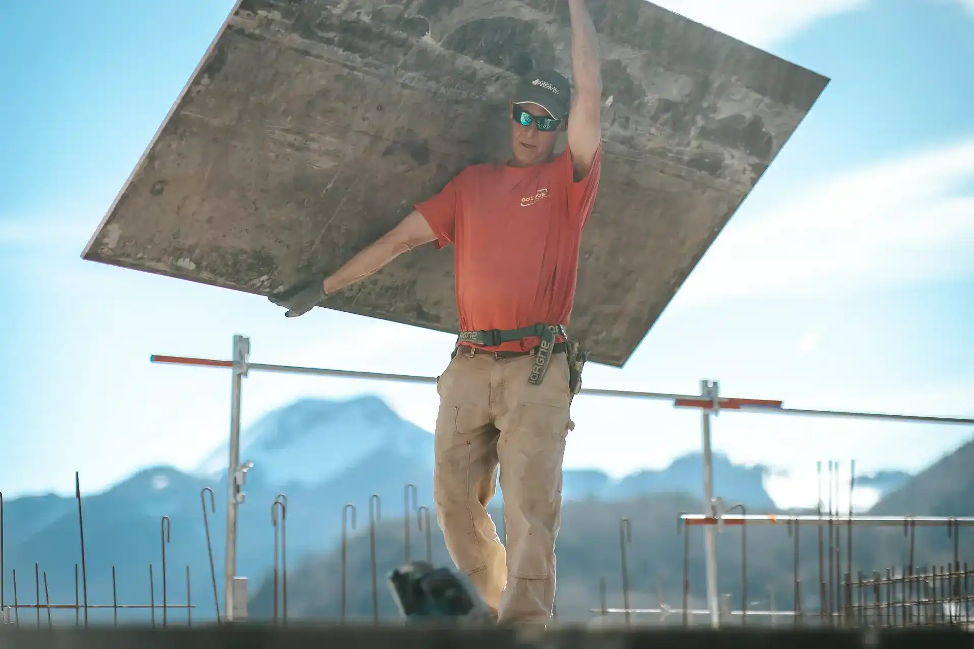 Maçon portant un panneau de coffrage sur un chantier de montagne